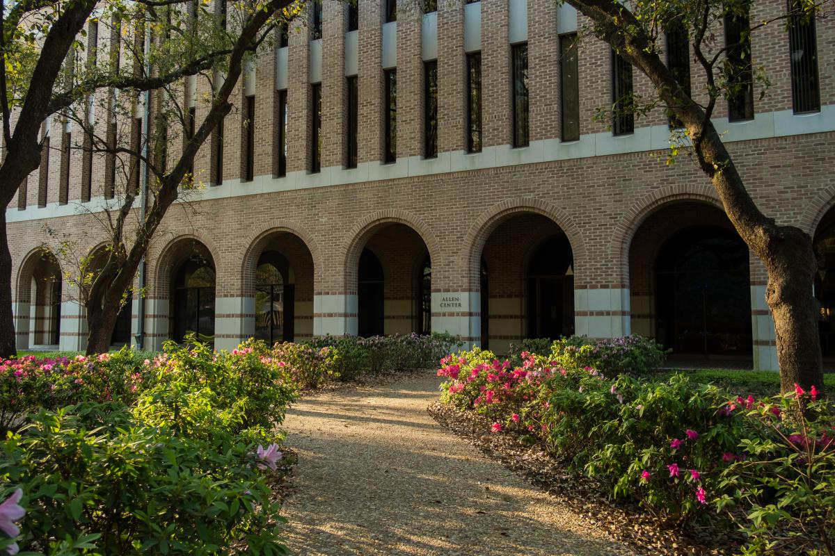 Photo shows flower-lined sidewalk leading to the front of the Allen Center.